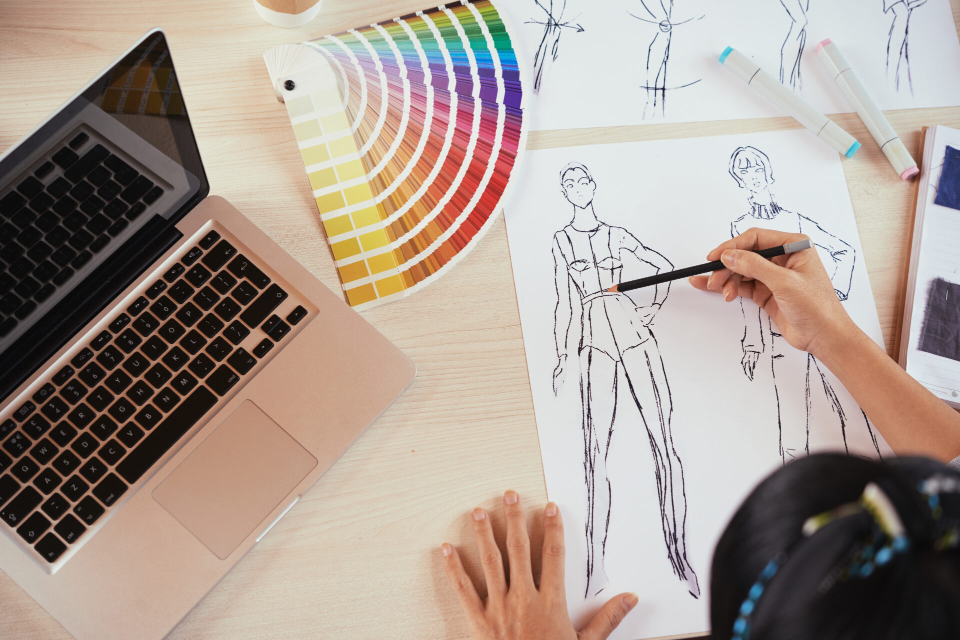 uniform designer sketching near laptop