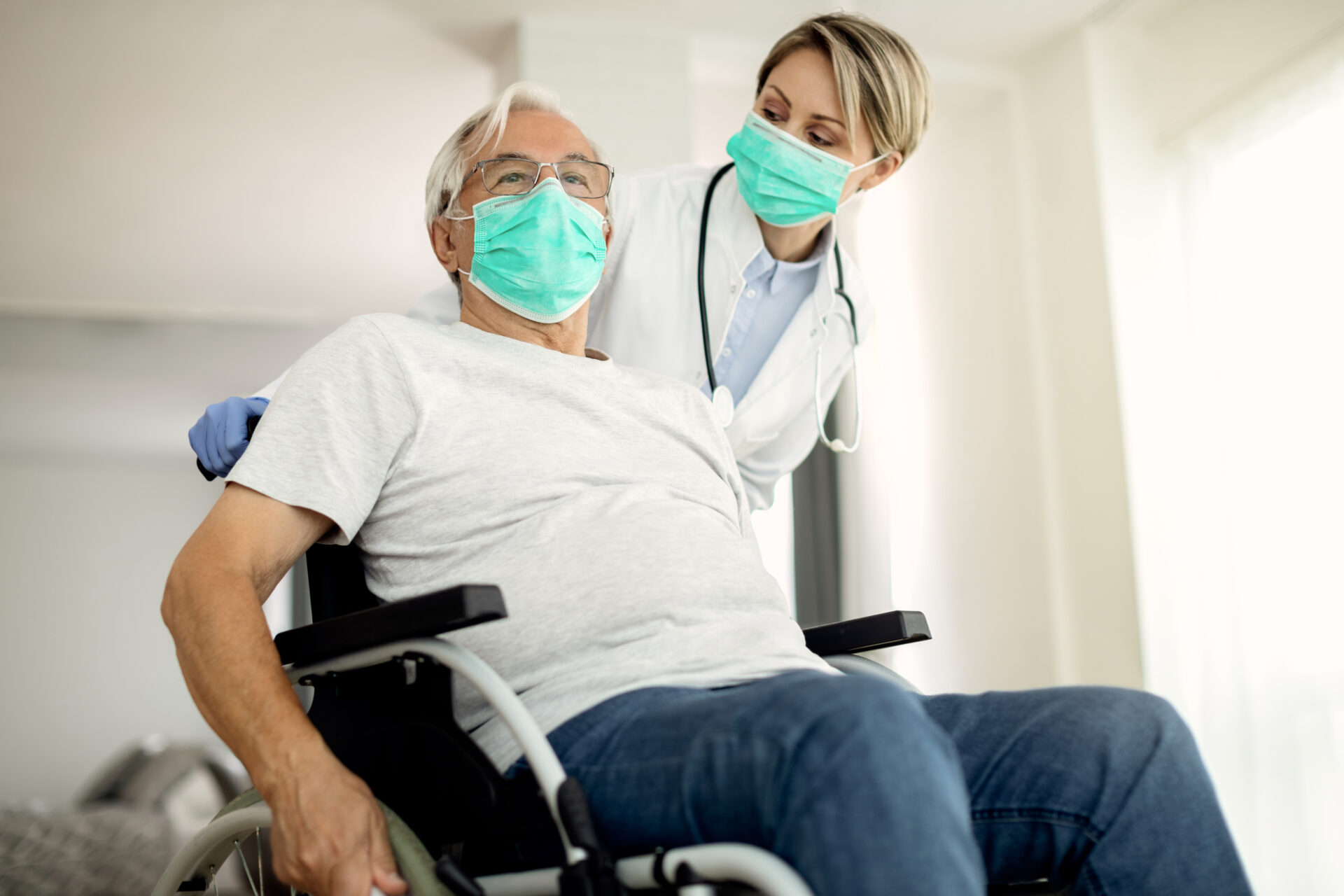 man in wheelchair with his doctor - healthcare uniform